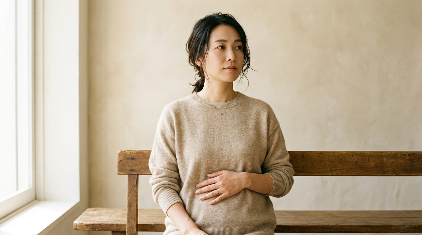 下腹部に手を当てて気になる様子の30代女性