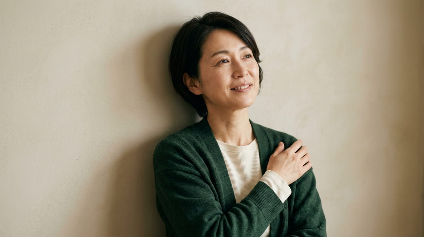 二の腕にそっと手を添えて、ほっとした表情を見せる40代の日本人女性